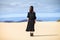 Back view of young lonely woman in long black dress in desert on