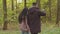 Back view young loving carefree joyful hispanic couple walks in autumn park in nature enjoying weekend together walking