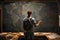 Back view of a young man with a backpack standing in front of a blackboard with a world map