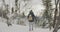 Back view of young man tourist walking in snowy forest on winter day