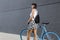 Back view, young pretty woman walking with her bicycle,