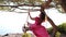 Back View at Young Resting woman in beautiful pink long dress swinging on a swing near the sea