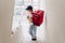 Back view of young rider woman wearing red backpack holding paperboard box in neighborhood stairs. Delivery service concept.