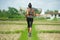 Back view of young runner woman with attractive and fit body in running outdoors workout at beautiful off road track green landsca