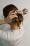 Back view of a young slavic woman styling her natural dark blonde hair in a messy ponytail.