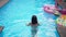 Back view of young slim Caucasian woman entering azure blue pool swimming in slow motion. Brunette Caucasian female