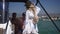 Back view young slim confident woman in straw hat with backpack looking around enjoying trip on sailboat. Caucasian