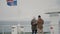 Back view of young stylish couple standing on the board of the ship with Icelandic flag. Man and woman look on the sea.