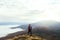 Back view of young tourist hiker with backpack standing on the top of the mountain and looking at beautiful yellow