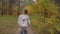 Back view of young woman with backpack walking in autumn park - steadicam shot