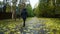 Back view young woman in black jacket with a hood walking on path in autumn day