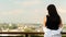 Back view of a young woman in a black T-shirt and white shirt, a brunette traveler looks at the cityscape on a summer sunny day