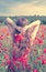 Back view of a young woman with long blonde hair in a red dress holding a bouquet of flowers in a poppy field