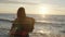 Back view of young woman with plaid enjoying the sunset on the windy beach with stretched arms. Freedom concept.