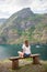 back view of young woman sitting on wooden bench and looking at majestic landscape Aurlandsfjord Flam