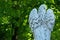 Back viwe of white beautiful angel with wings against green forest. Ancient stone statue. Copy space for design or text