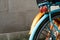 Back wheel of orange and blue bycicle with concrete wall design retro hipster