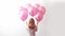 back of woman with bunch of pink helium balloons on white background