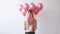 back of woman with bunch of pink helium balloons on white background