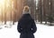 Back of woman in casual winter clothes looking at snowy wood scenery. Outdoor hiking in snow