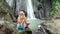 Back of woman meditating at the beautiful waterfall in green tropical rain forest in Bali