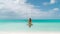 Back of woman on a swing over turquoise ocean