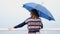 Back of woman with umbrella relaxing on the pier. Sea.