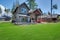 Back yard with fire pit and red chairs near newly bild luxury real estate home with forest biew and green grass