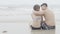 Back young asian couple sitting hug at the beach honeymoon with romantic together.