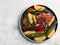 Backed chicken with potatoes on a round plate on a light gray background