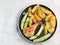 Backed chicken with potatoes on a round plate on a light gray background