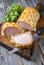 Backed Kasseler pork steak as piece and slice in puff pastry and egg yolks on a wooden cutting board with herbs
