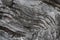 Background on the basis of the texture of rock. Black and gray stone with wavy inclined layers and cracks