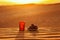 On the background of the beautiful sunset sun in the desert is a glass of water and dates in a plate