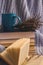 Background of blue hand-knit plaid and pillows in cosy home with dried bouquet of lavender flowers, books, mug of coffee, garland.