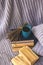 Background of blue hand-knit plaid and pillows in cosy home with dried bouquet of lavender flowers, books, mug of coffee, garland.