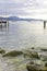 In the background a boardwalk leads into Lake Garda. In the foreground are large pebbles and stones overgrown with algae