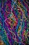 A background of brightly colored Mardi-Gras beads on a purple b