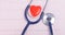 On the background of a cardiogram, a blue phonoscope and an image of a red heart, close-up, there is a place for inscription