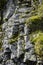 Background of coarse layered stone rocks, full frame. Rough stone texture of mountains. The stones are covered with moss