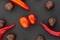 Background contrasting cherry tomatoes in the center of chili pepper chestnuts brown nuts closeup on a dark background