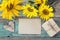 Background with empty card, sunflowers and gift box on old wooden boards with peeling paint.
