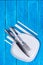Background with empty squared white ceramic plate and silver cutlery on blue wooden boards. Copyspace. Vertical photo.