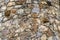 Background of the facade of an old oval tower made of stones of different rocks from raw natural stone