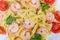 Background of farfalle pasta with shrimp tails and cherry tomatoes