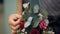 In the background female hands filling florist bouquet decorations