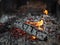 Background of fireplace with gloving embers. Close up view on smouldering fire. Embers burning with red and yellow flame