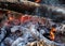Background of fireplace with gloving embers. Macro shot of smouldering fire. Embers burning with red flame. Texture of ash and