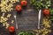 Background with fork and knife pasta, tomatoes and herb on dark