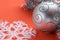 Background in the form of Christmas tree decorations - a large white snowflake, a silver ball and a silver rain on a coral